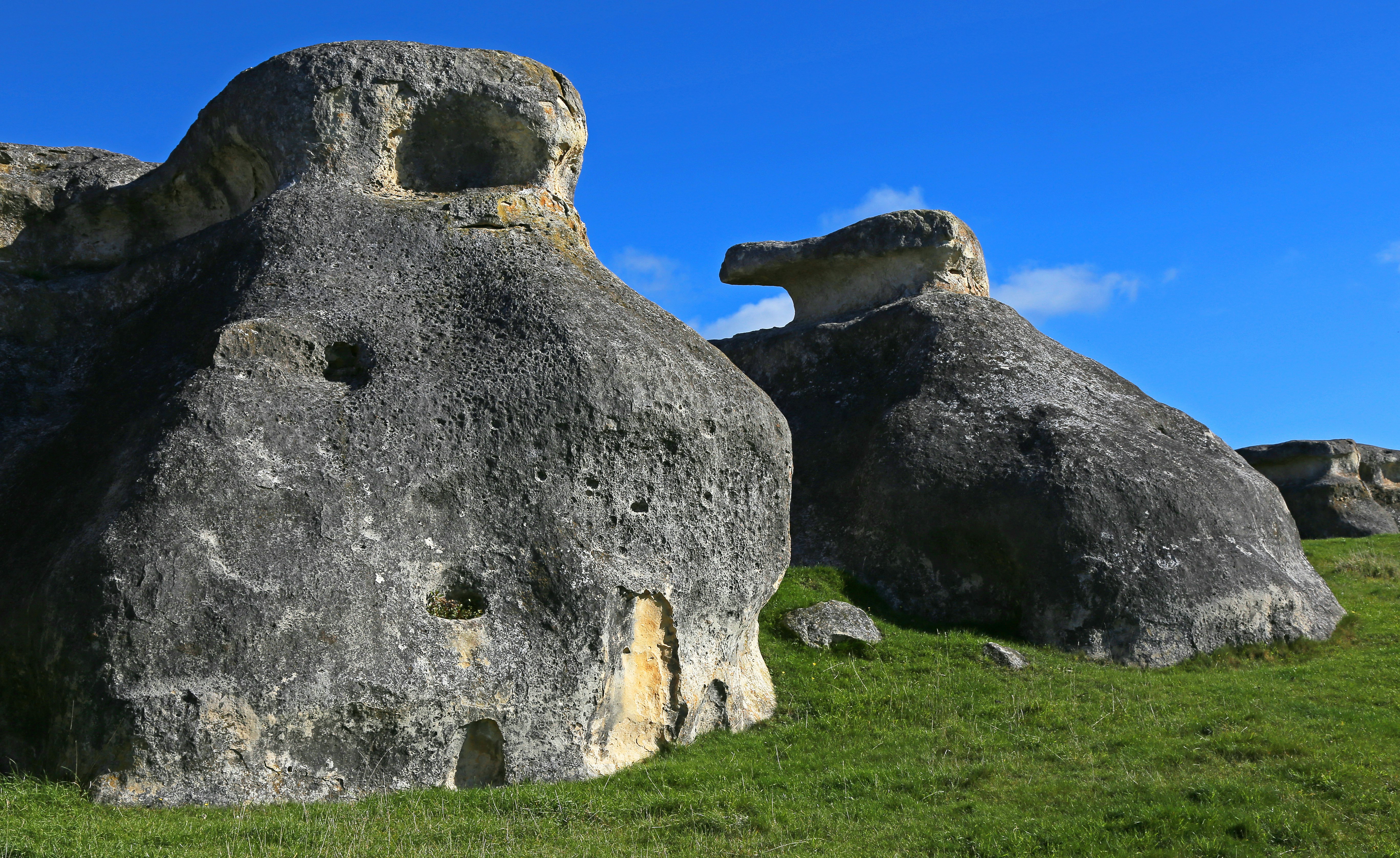 gray rock formation on green grass field under blue sky during daytime
